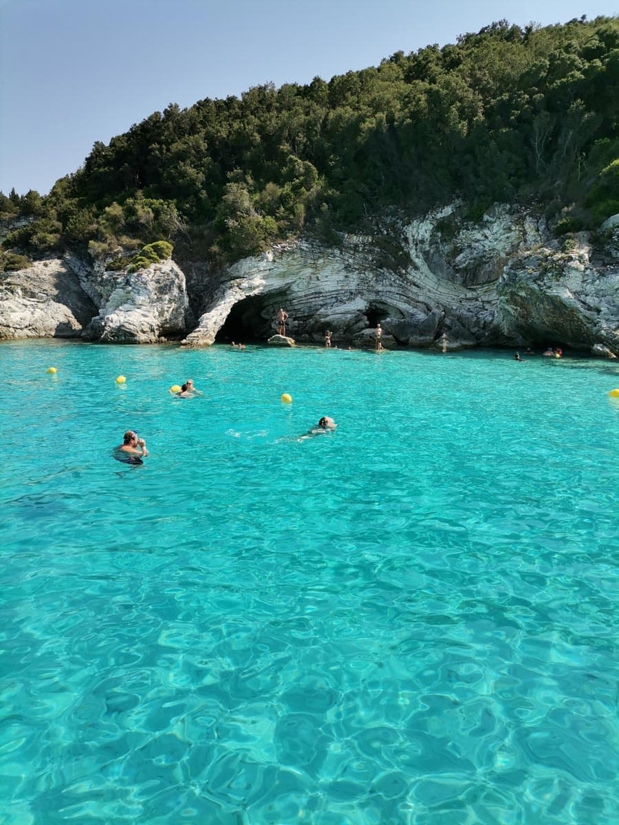Snorkelers swimming in vibrant turquoise sea near Corfu sea caves