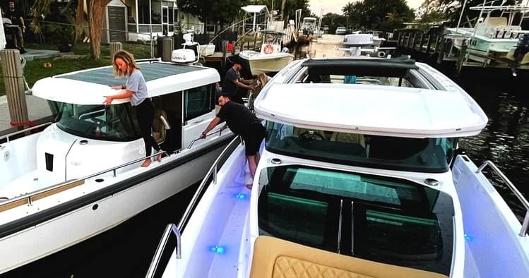 Docked motor yachts alongside marina with crew preparing gear