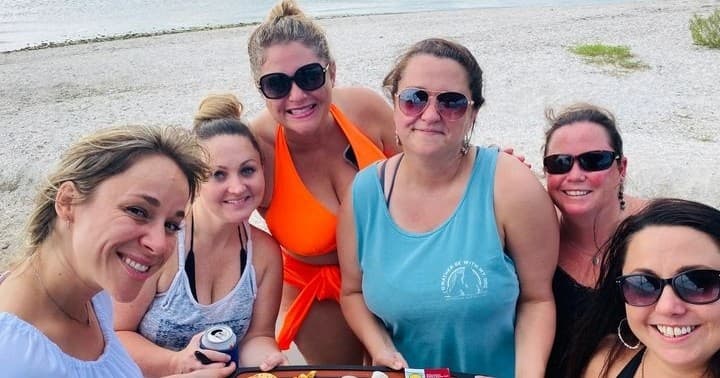 Group of friends smiling on sandy beach after boat excursion