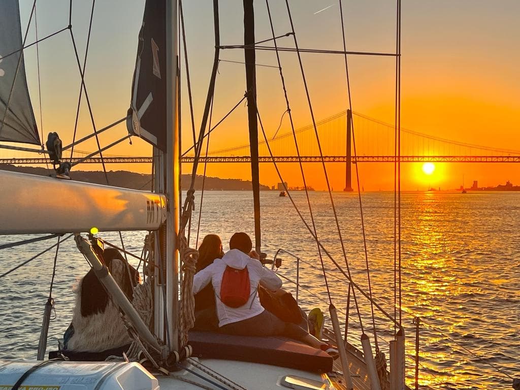 Couple sailing at sunset with Lisbon bridge skyline view