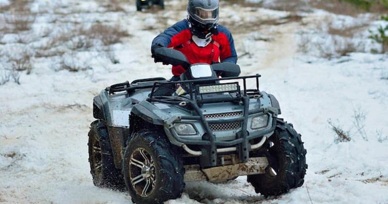 ATV rider traversing snowy trail in winter mountain landscape