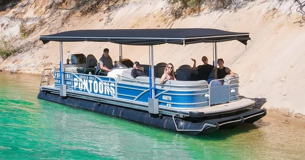 Group enjoying pontoon tour along turquoise inlet near dunes