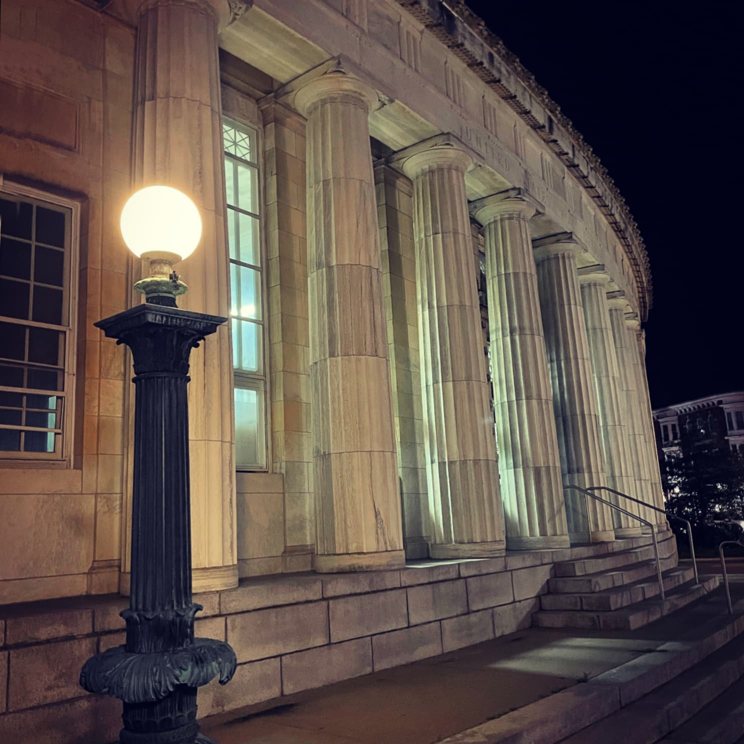 Lit seaside courthouse columns at night on coastal promenade