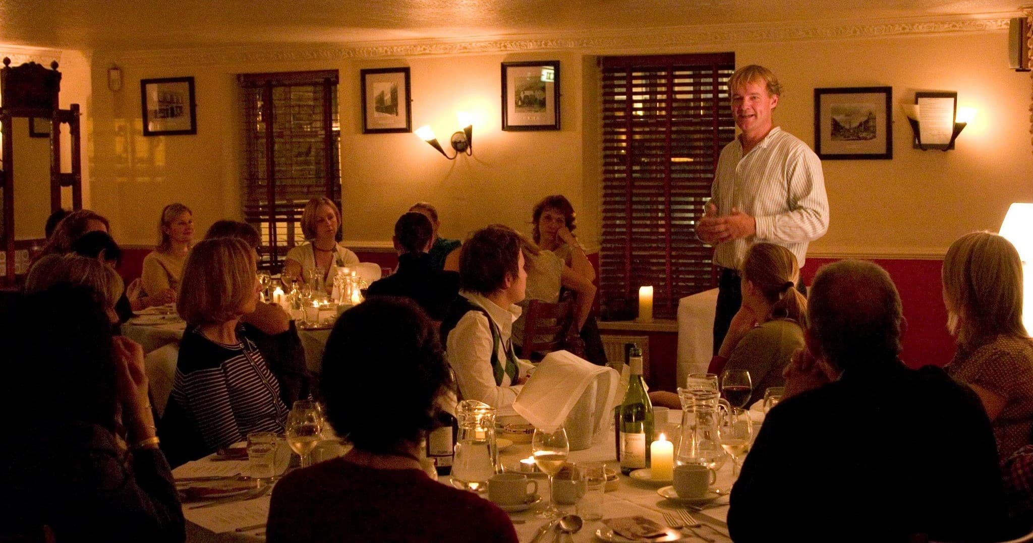 Guide delivering storytelling performance to seated pub guests