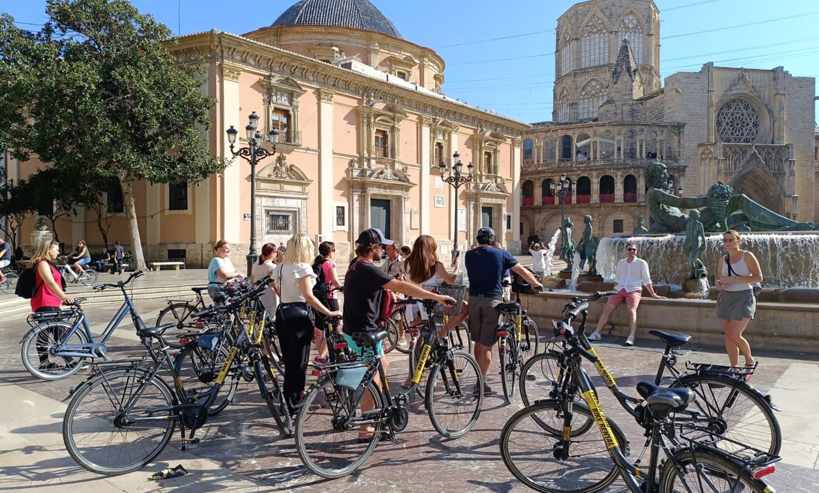 Guided bike tour group exploring Valencia plaza by cathedral
