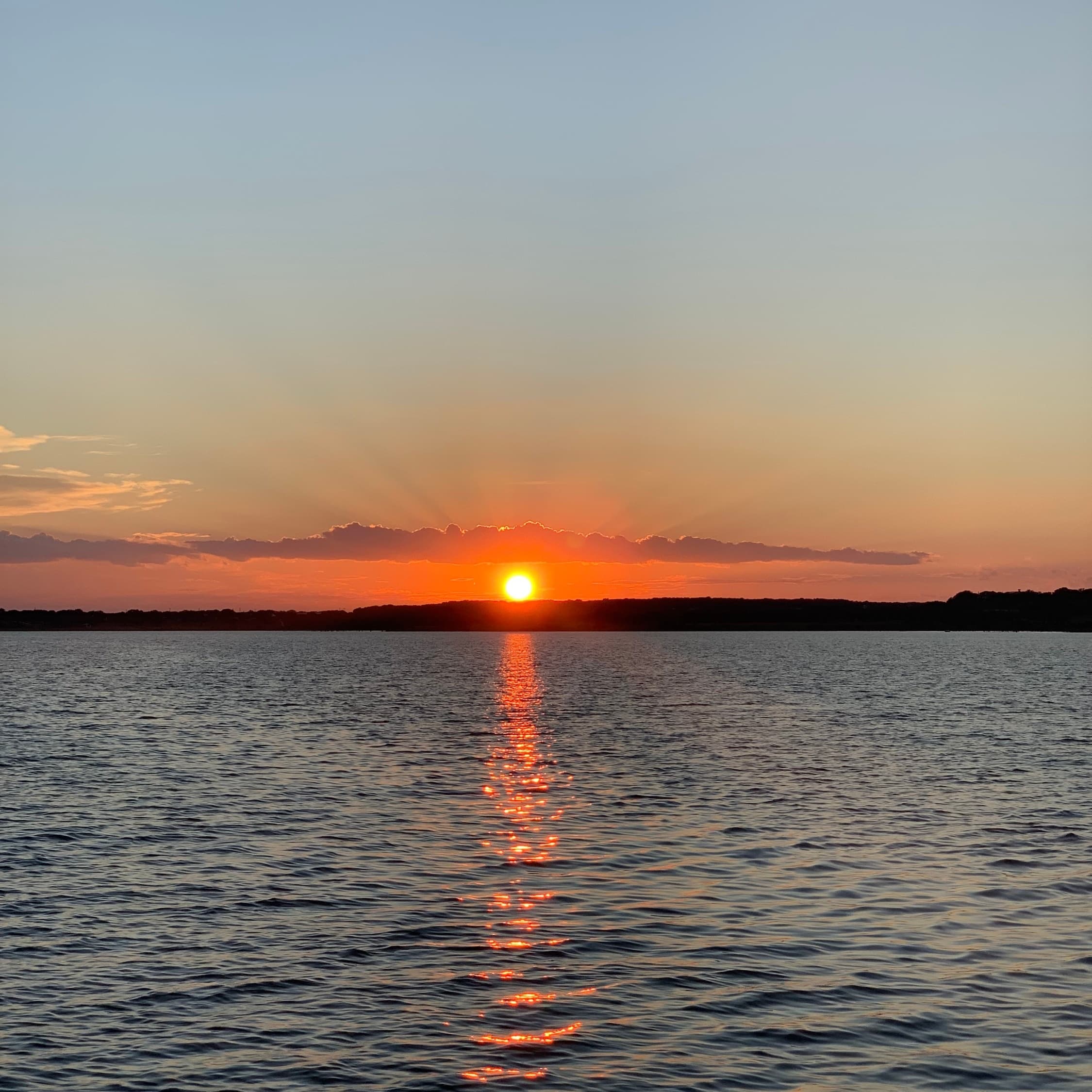 Sunset over lake with calm water reflection, scenic boating vista