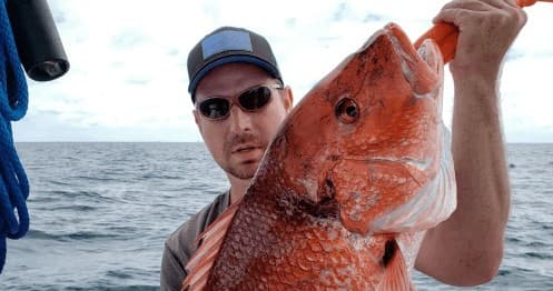 Angler holding trophy red snapper aboard offshore charter