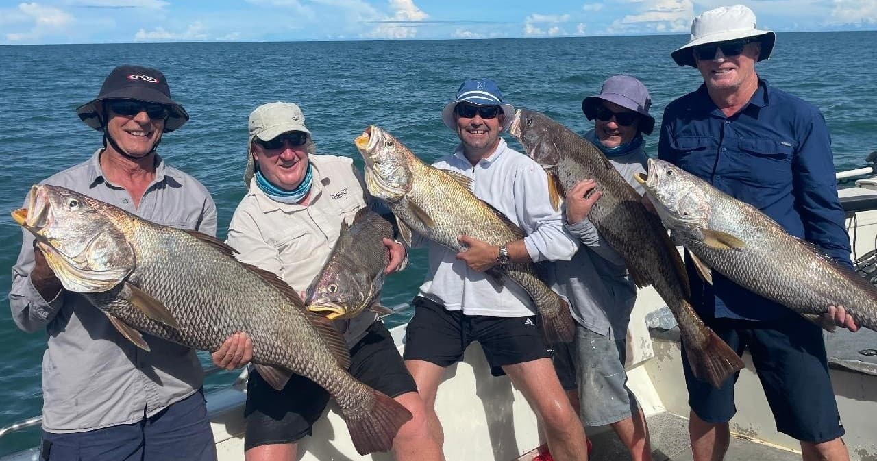 Anglers holding large reef fish aboard boat on blue ocean