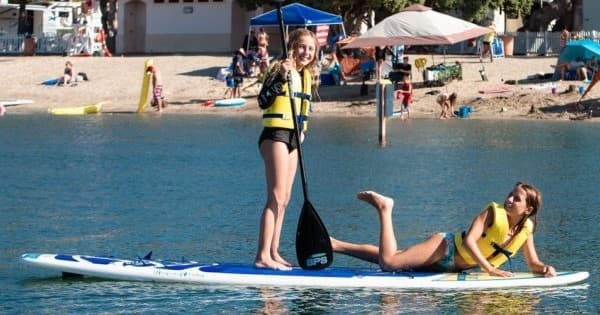 Two people paddleboarding and relaxing on Newport Dunes bay