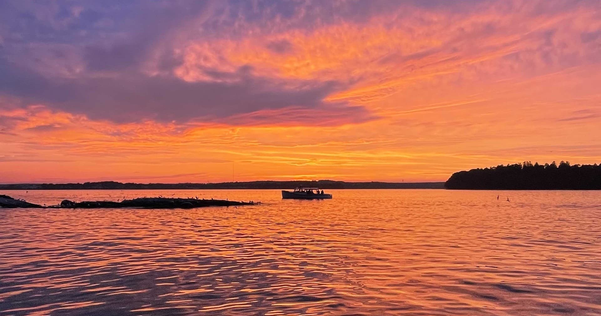 Sunset cruise over Casco Bay with vibrant orange and purple sky