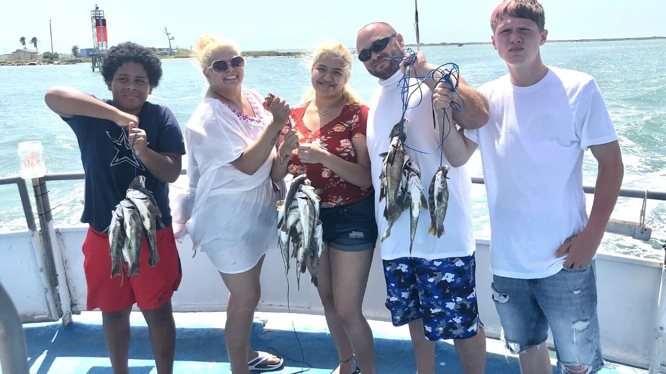 Group holding fresh-caught fish on a fishing boat, sportfishing trip