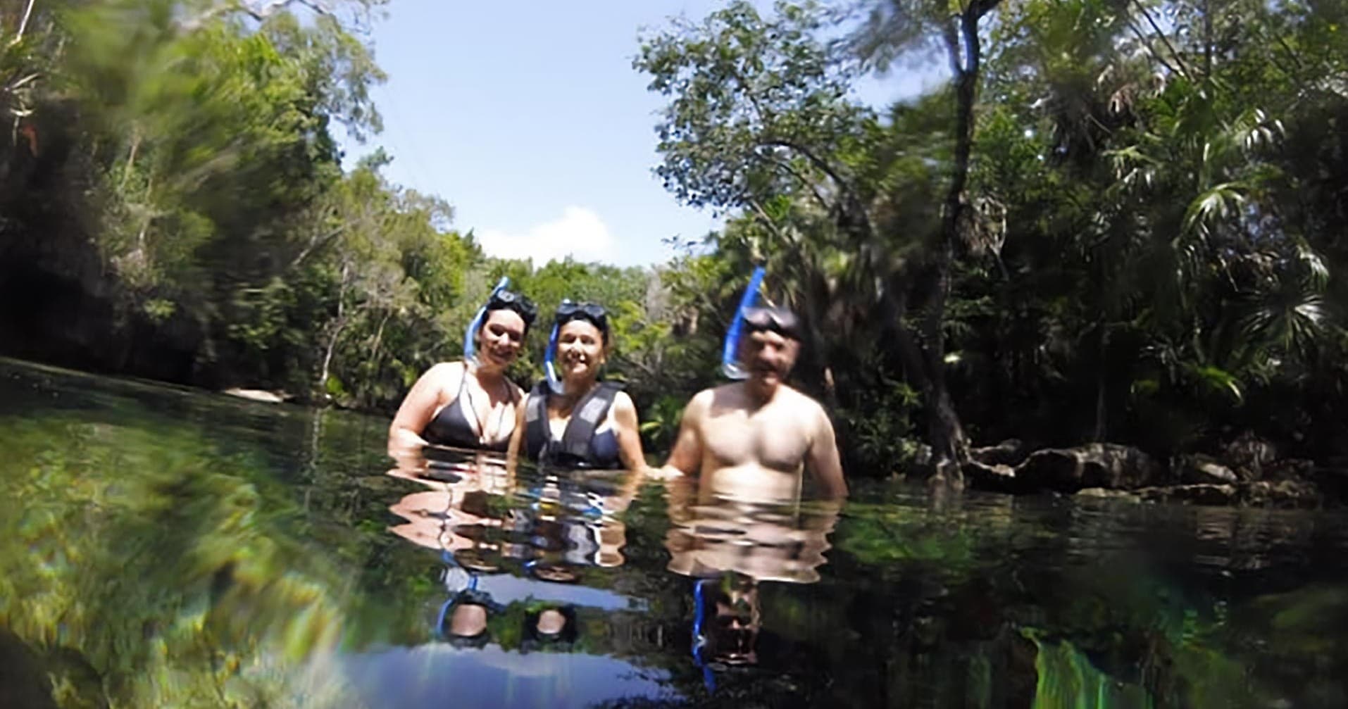 Group snorkeling in calm jungle river or cenote, outdoor water swim