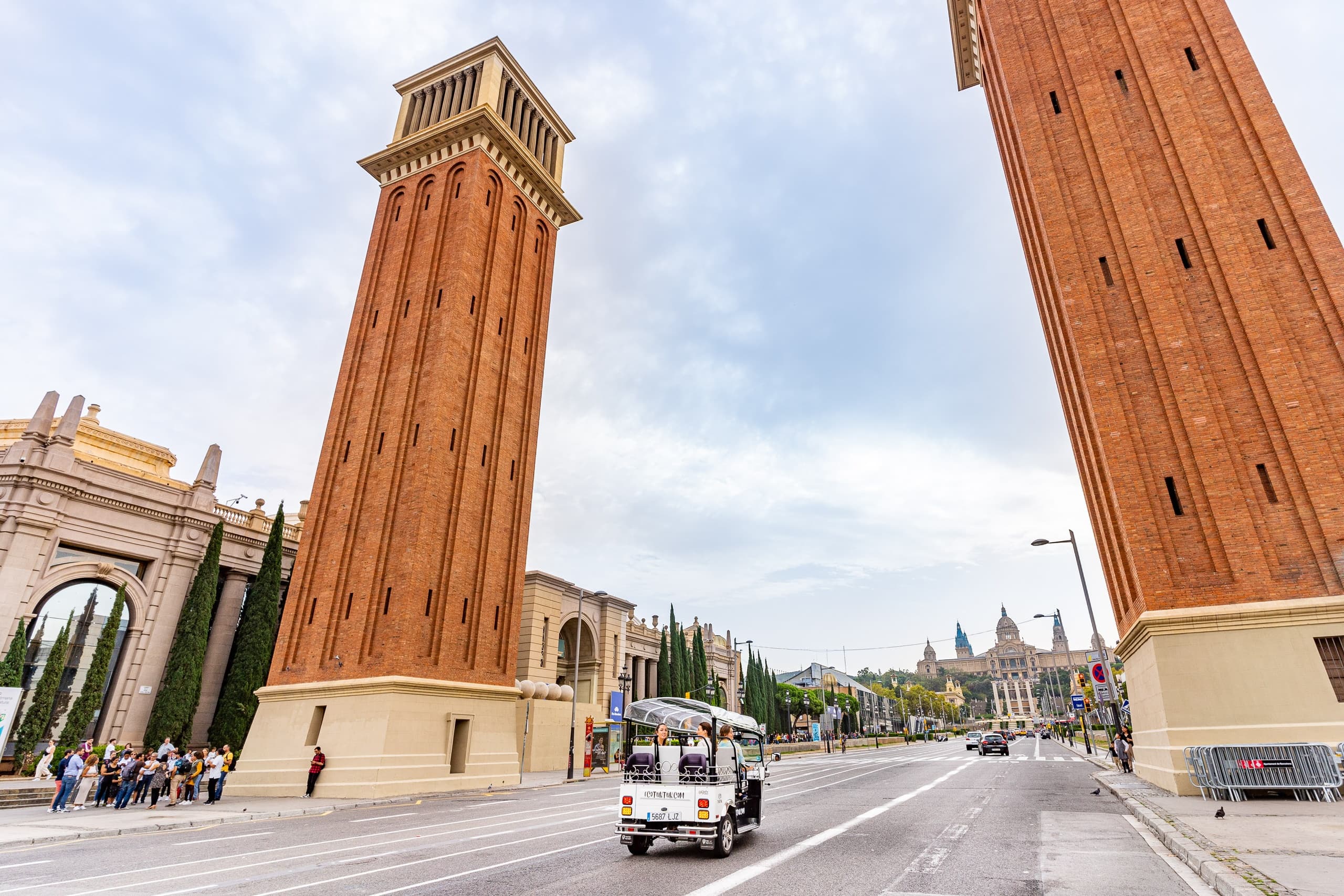 Electric tuk-tuk under twin Venetian towers in Barcelona plaza