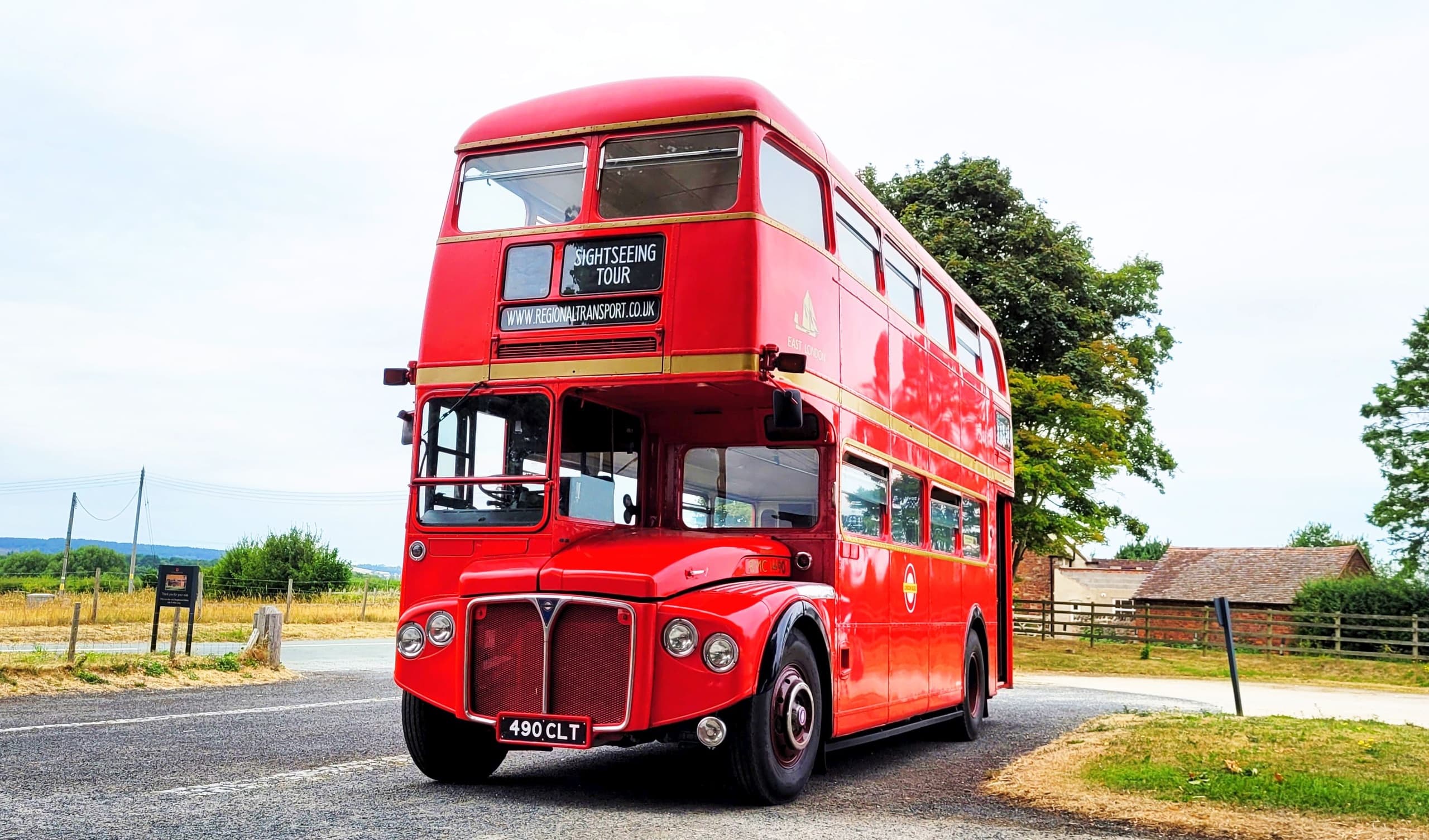 Vintage red double-decker bus on scenic rural roadside tour