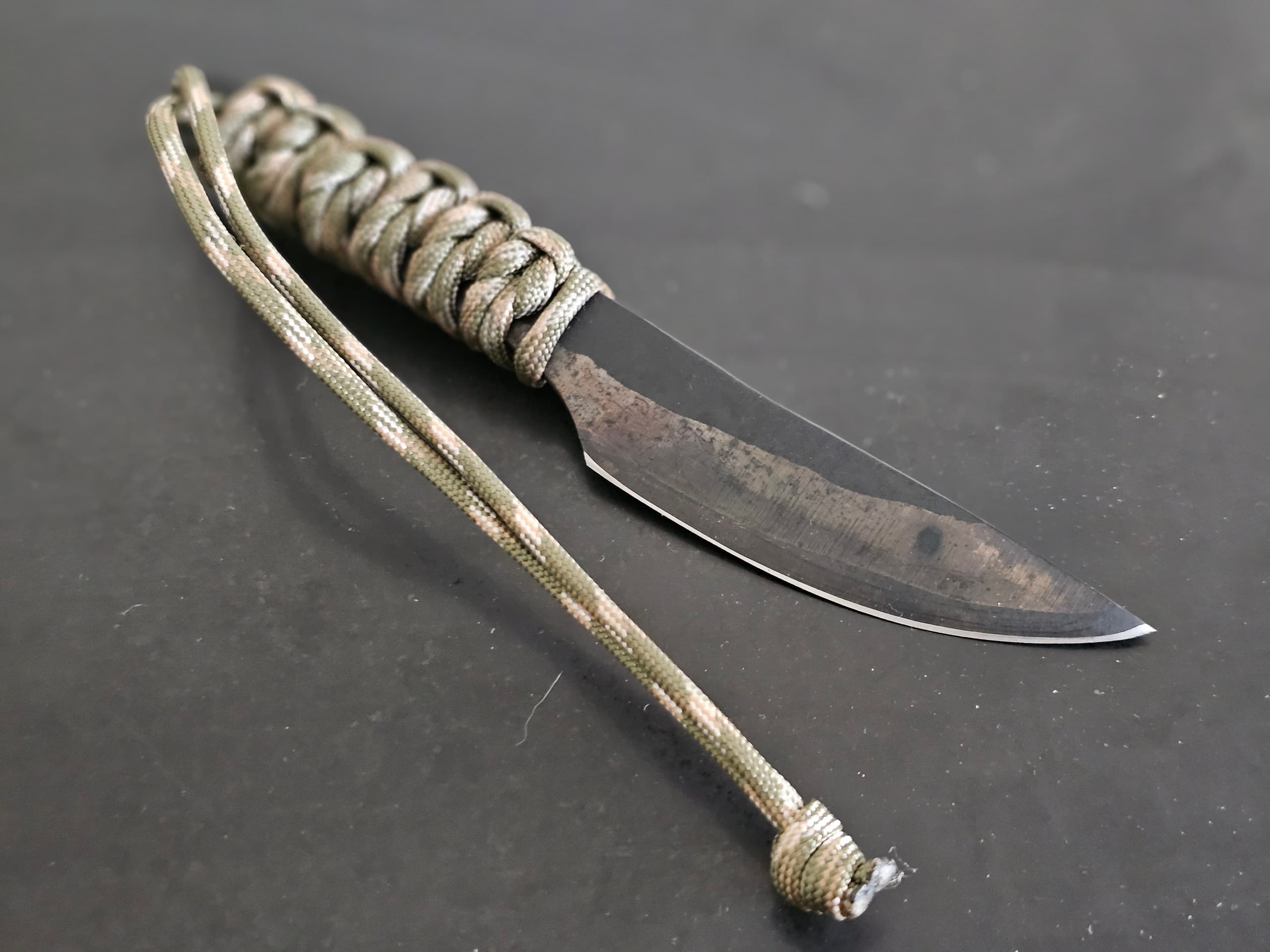Paracord-handled survival knife photographed on dark table