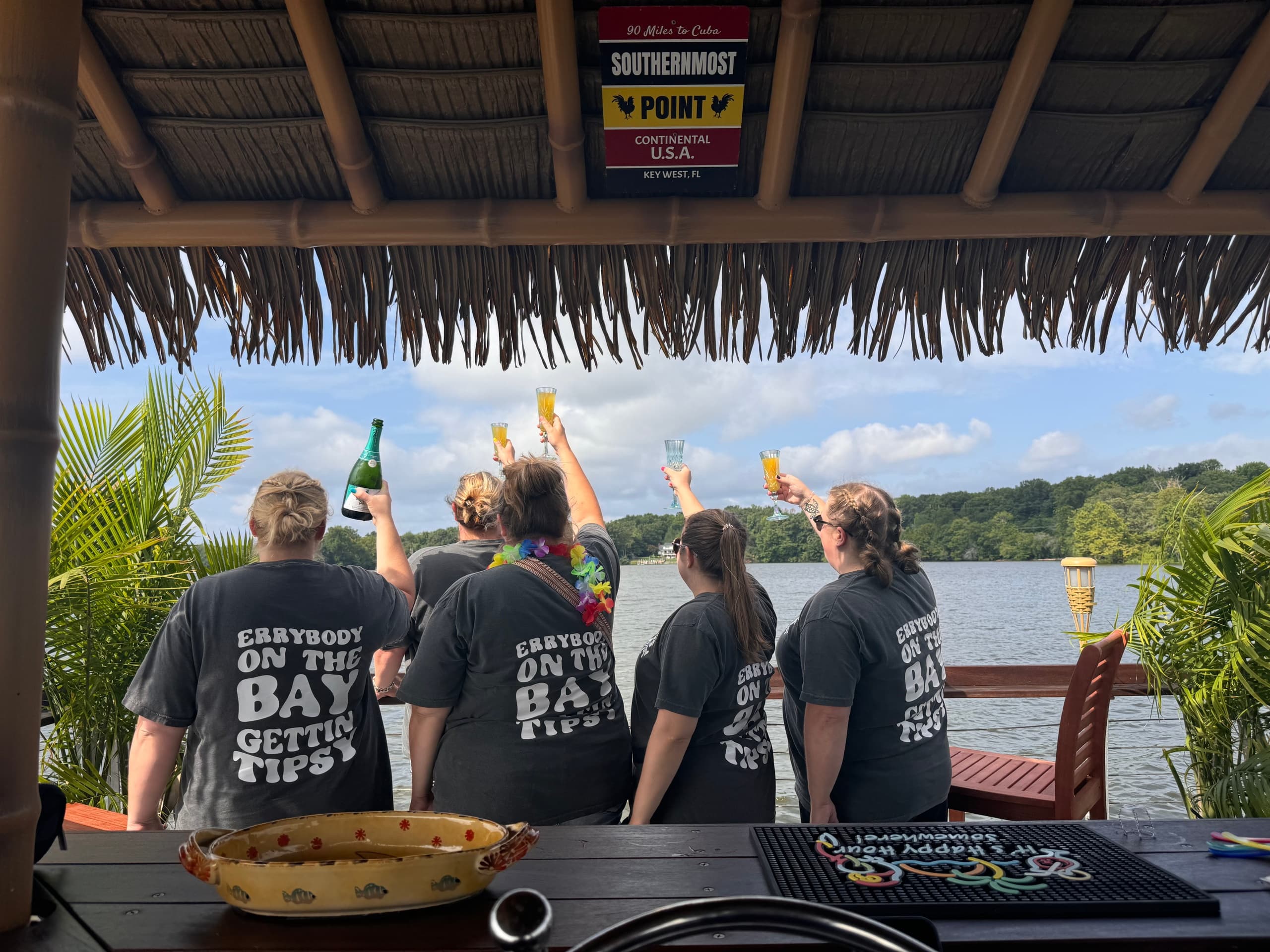Friends cheering with drinks aboard waterfront tiki bar
