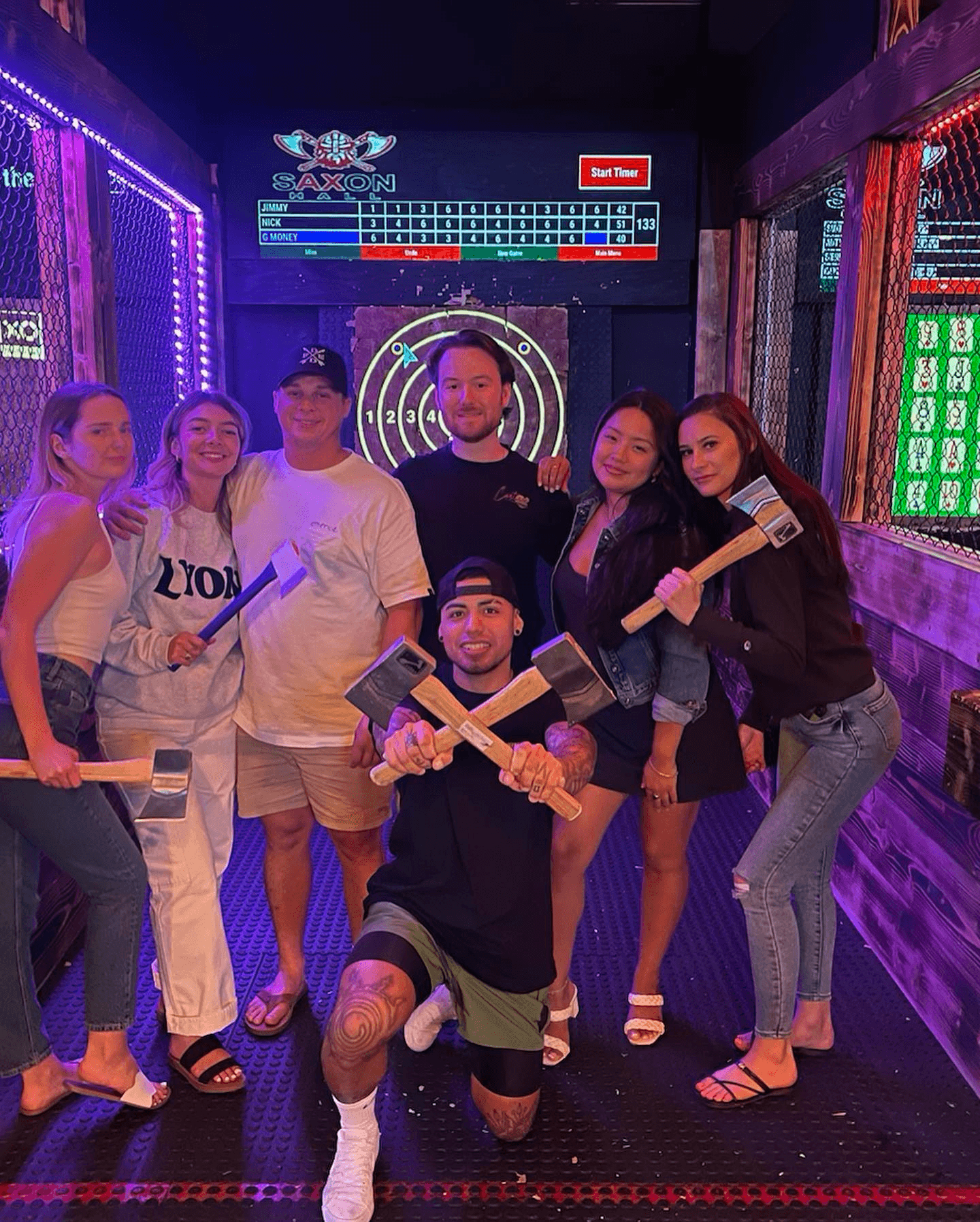 Group axe throwing at indoor venue posing with axes after game