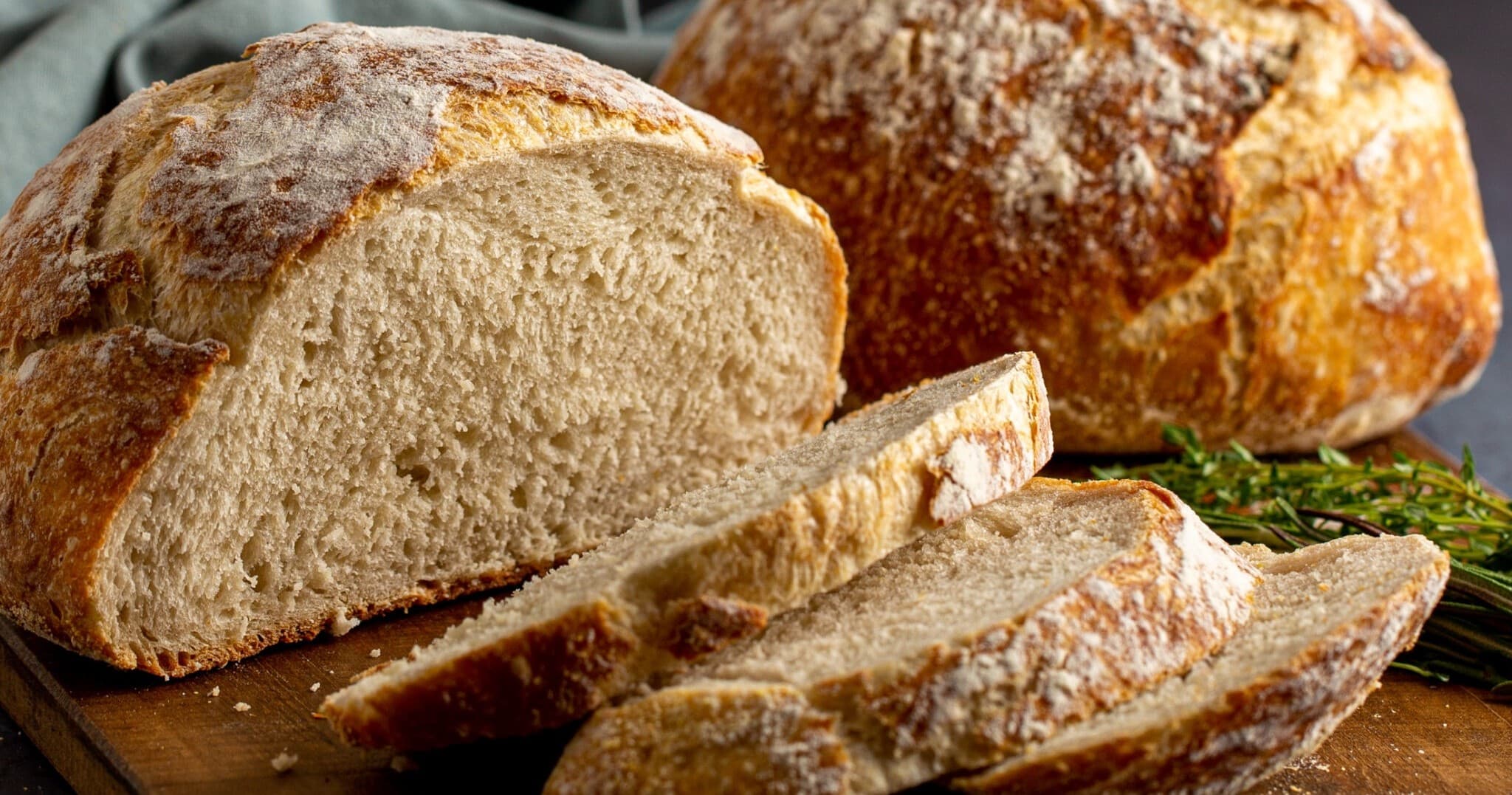 Sliced artisan sourdough loaf on wooden board, bakery scene