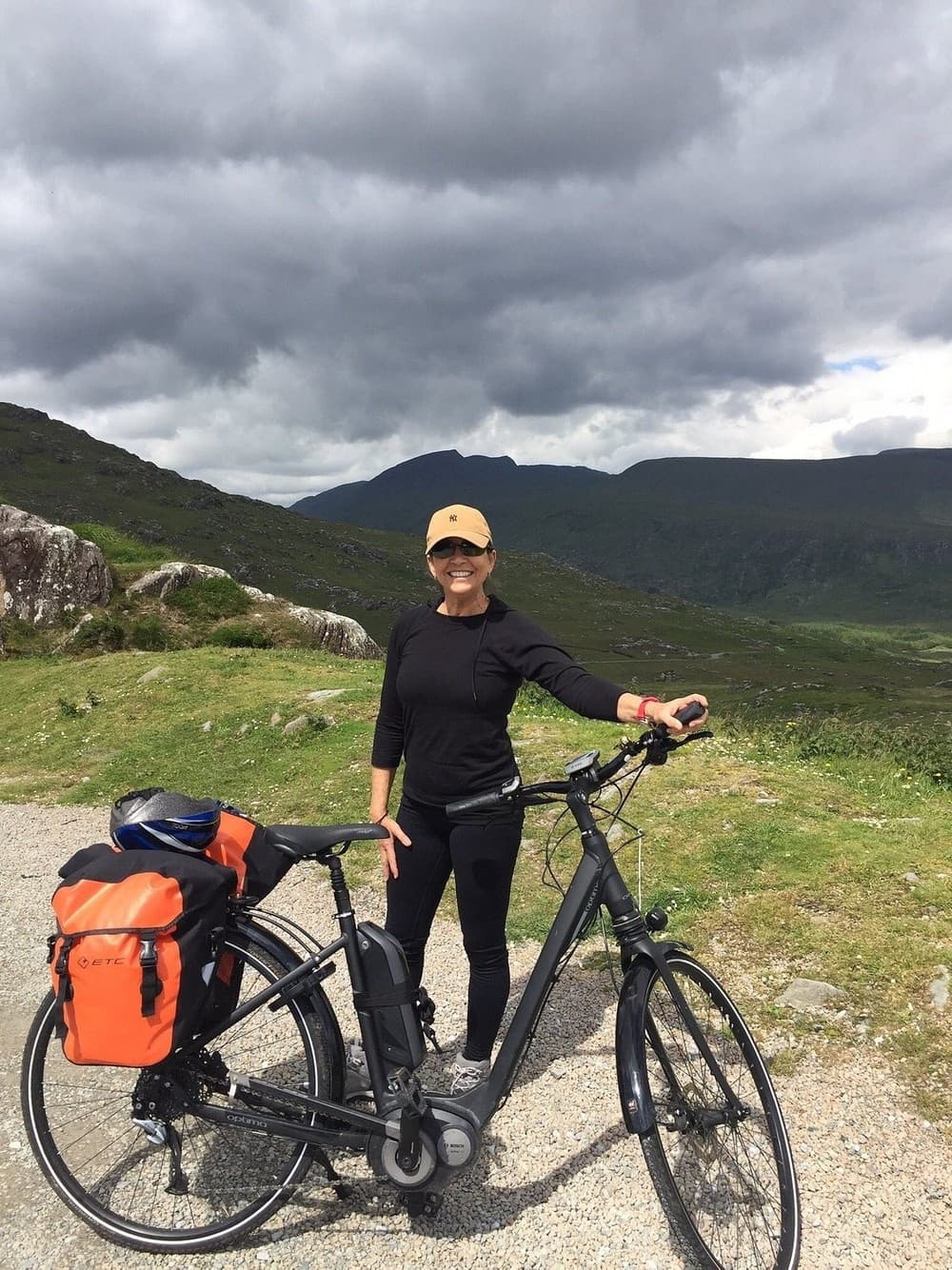 Woman standing next to rental bike on scenic Killarney road