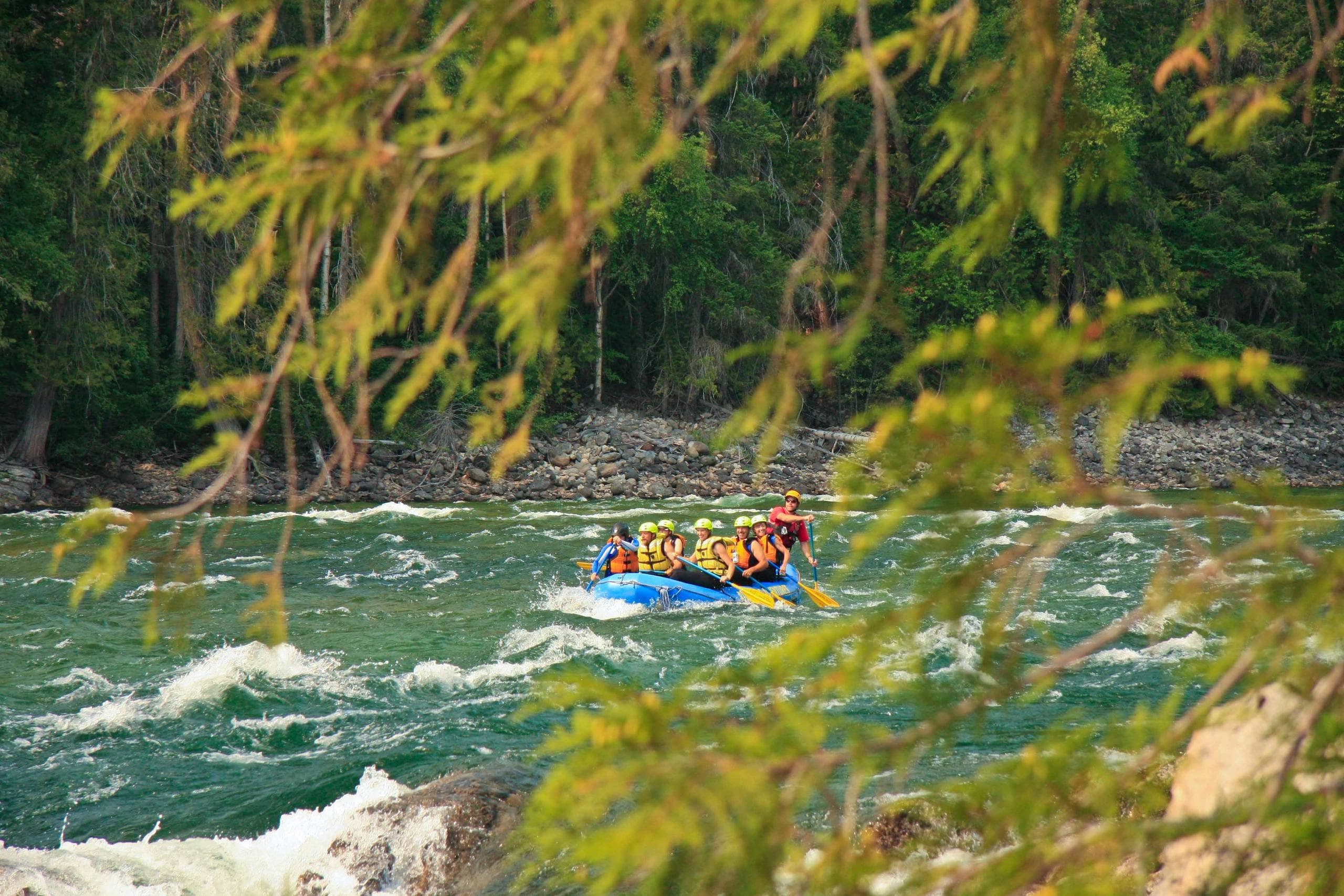 Rafting group navigating emerald river through forest canyon