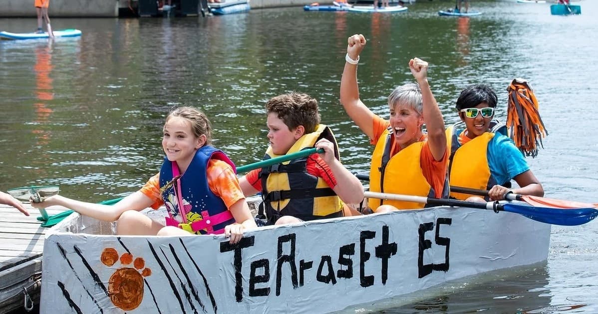 Kids paddling cardboard boat in community lake race