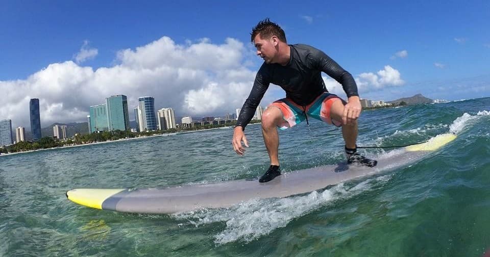 Stand-up surfer cruising near coastal skyline and clear water