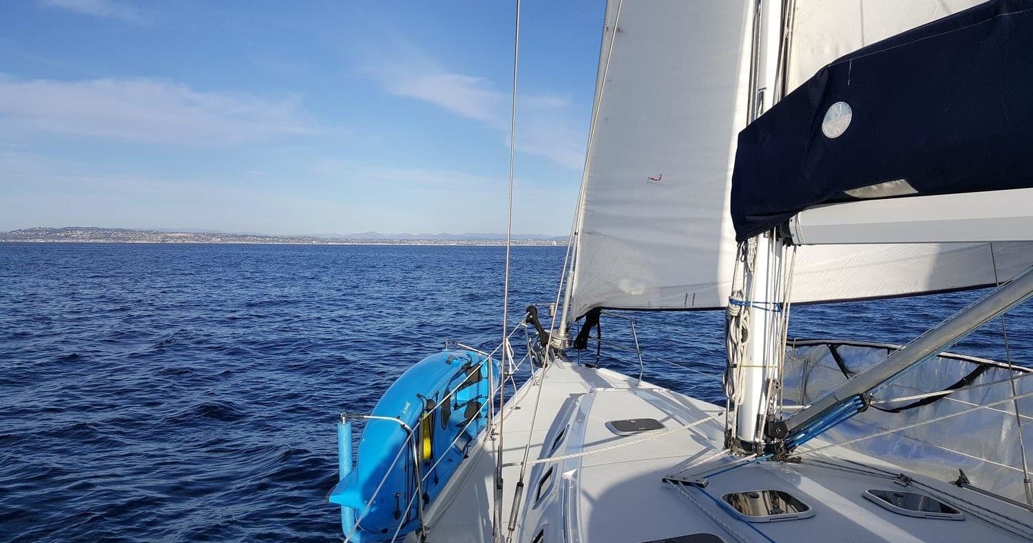 View from bow of sailboat on open ocean under blue sky