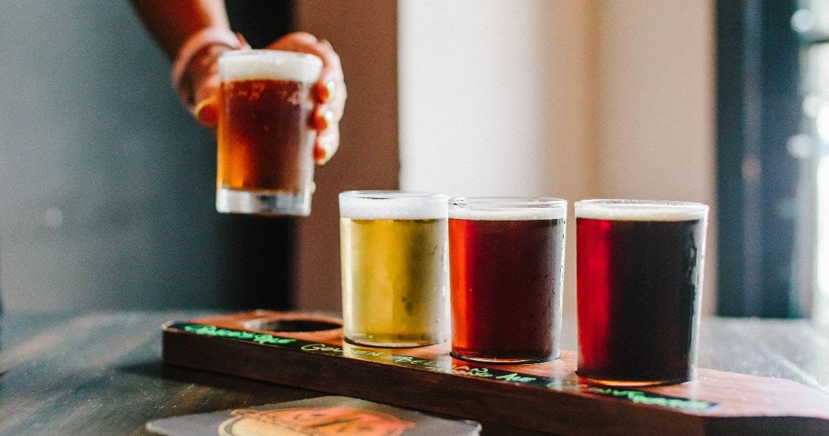 Flight of craft beers on wooden tray inside brewery tasting room