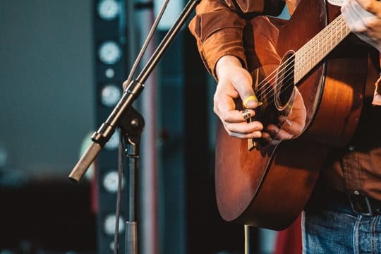 Acoustic guitarist performing on stage during live evening show