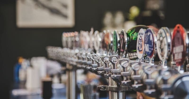 Row of beer taps at a craft brewery bar, indoor tasting
