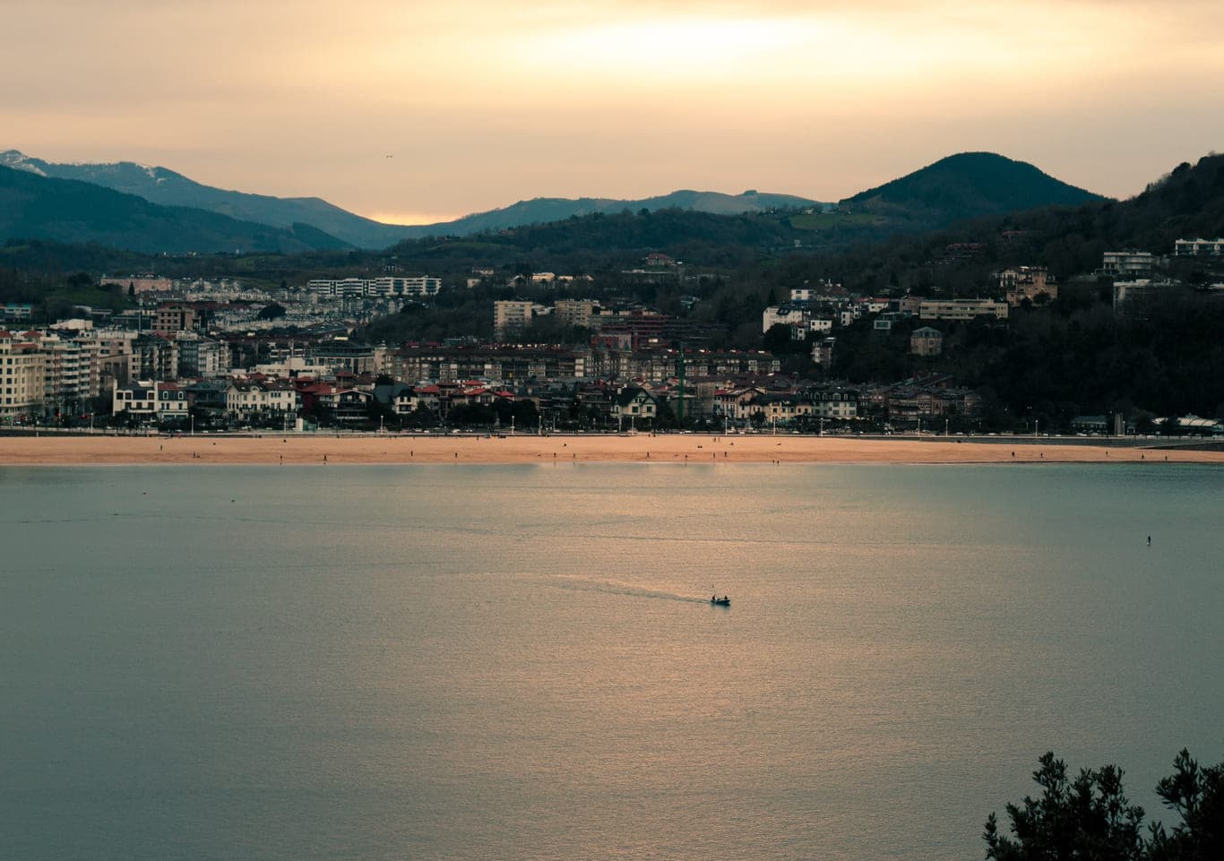 Coastal bay at sunset with calm waters and distant mountains