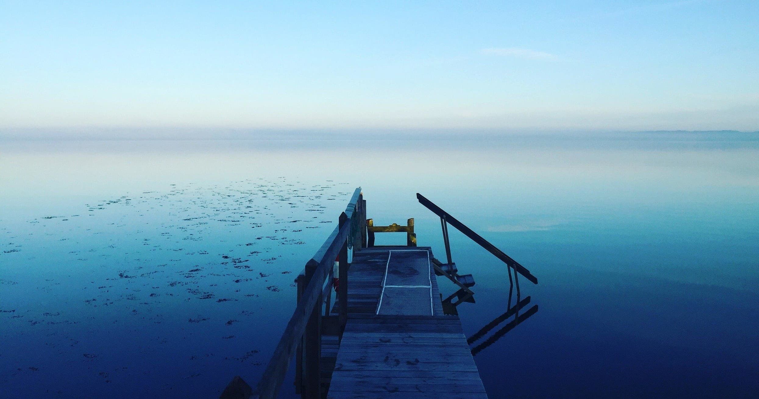 Wooden dock leading to tranquil Lake Keowee at dawn, calm water