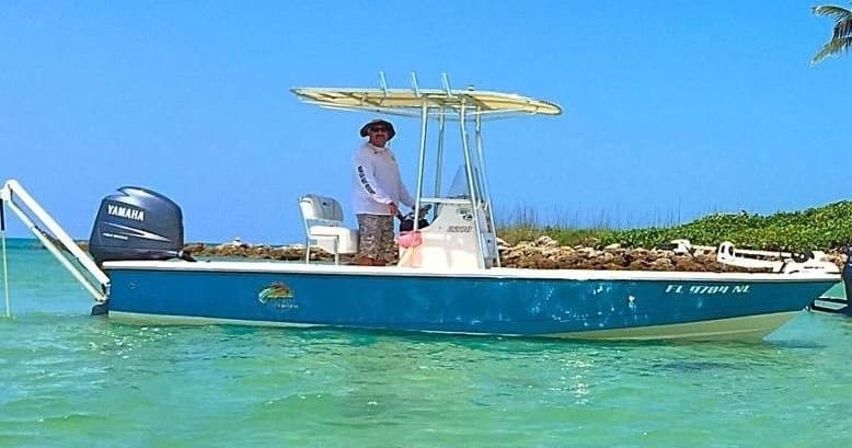 Skiff fishing in shallow turquoise flats with angler aboard