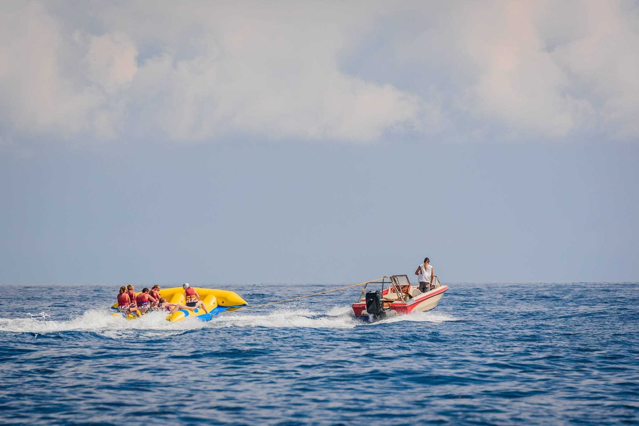 Boat towing inflatable banana boat across open Mediterranean sea