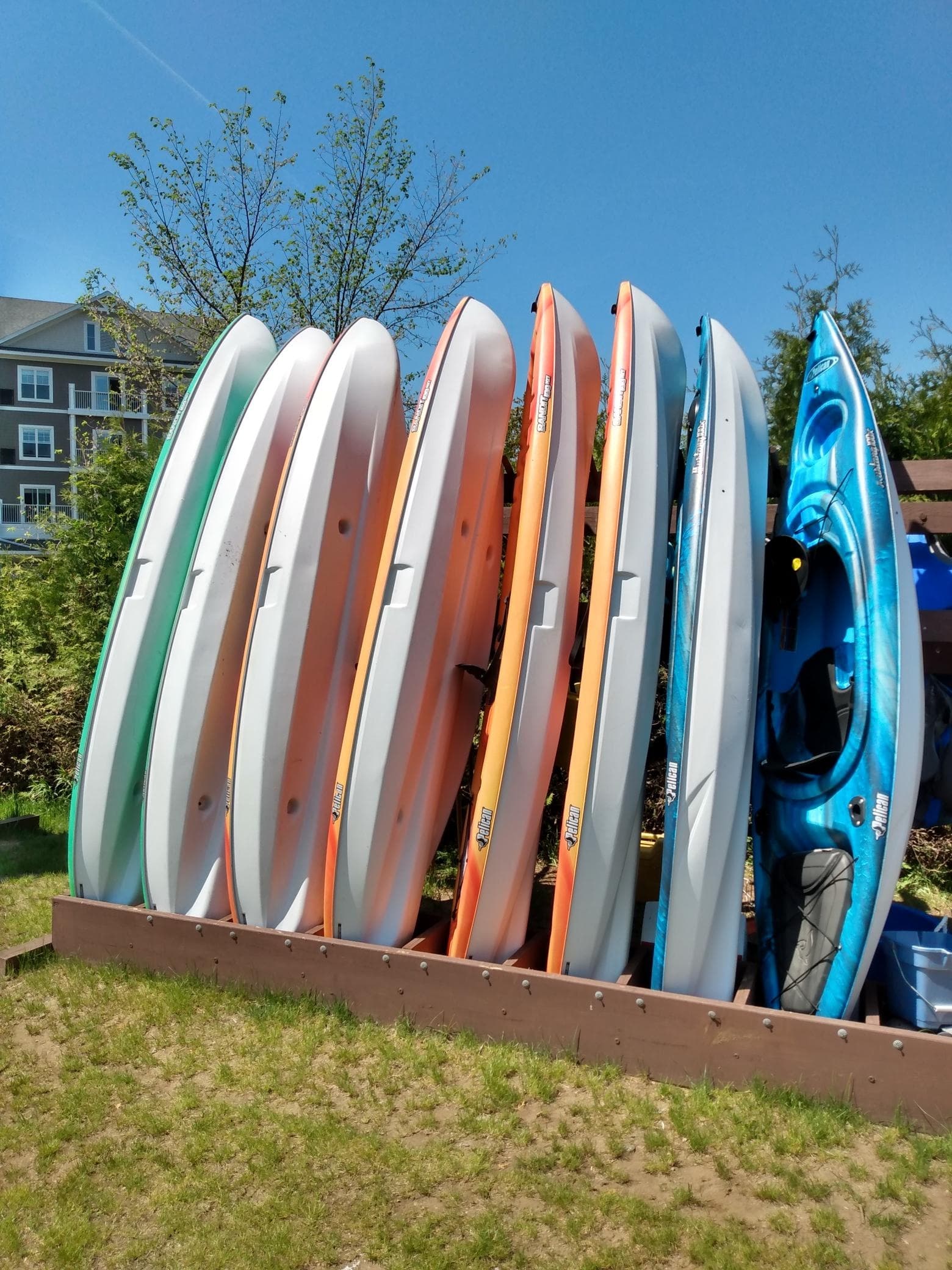 Colorful paddleboards and kayaks stacked on rack at lakeside