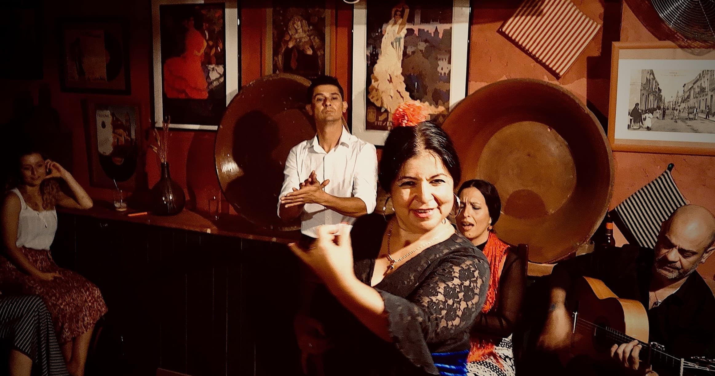 Female flamenco dancer smiling mid-performance in warm tablao setting