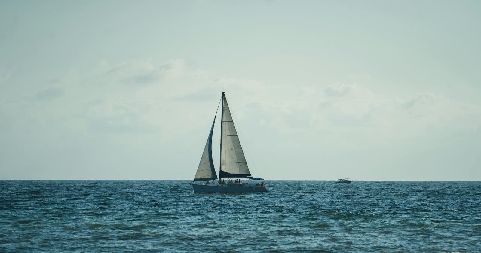 Single sailboat on open ocean horizon, peaceful coastal cruise