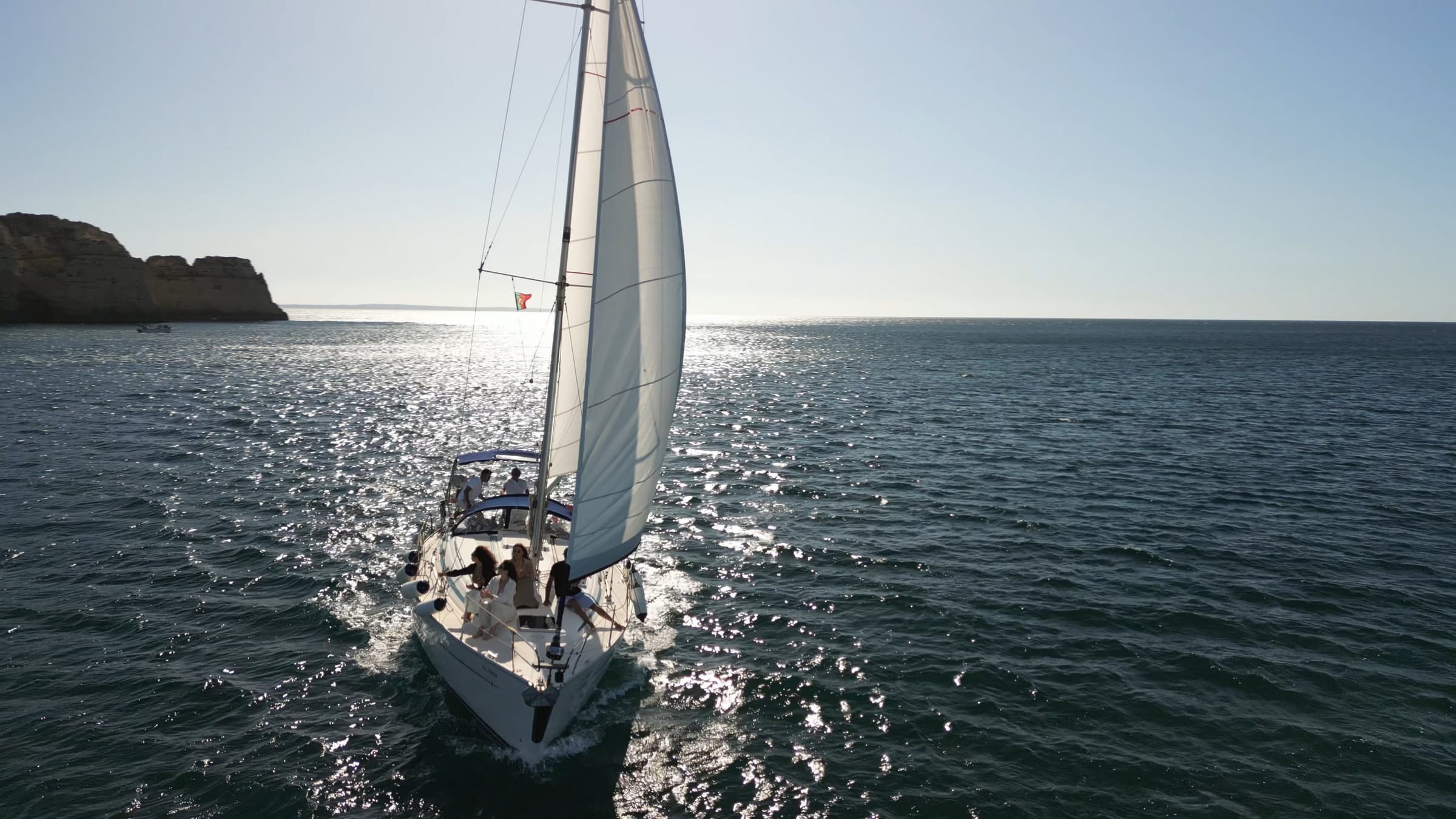 Sailboat cruising on open ocean with sun glint