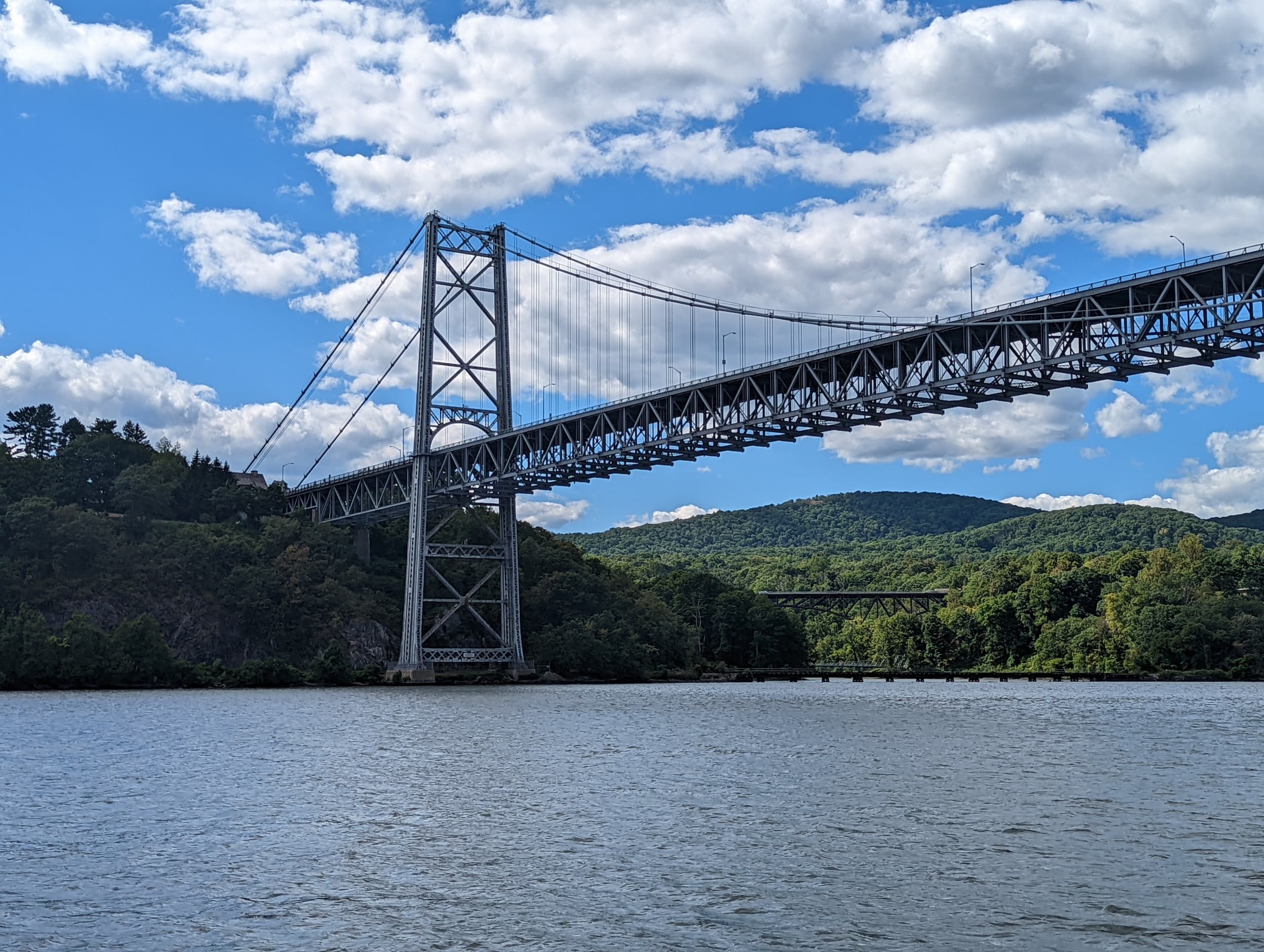Suspension bridge spanning river with scenic forested shoreline