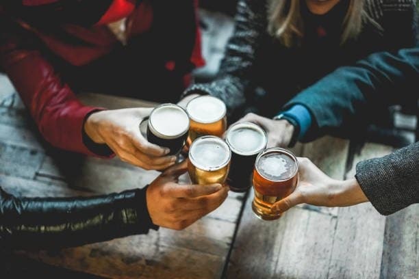 Friends clinking craft beers at cozy indoor tasting table