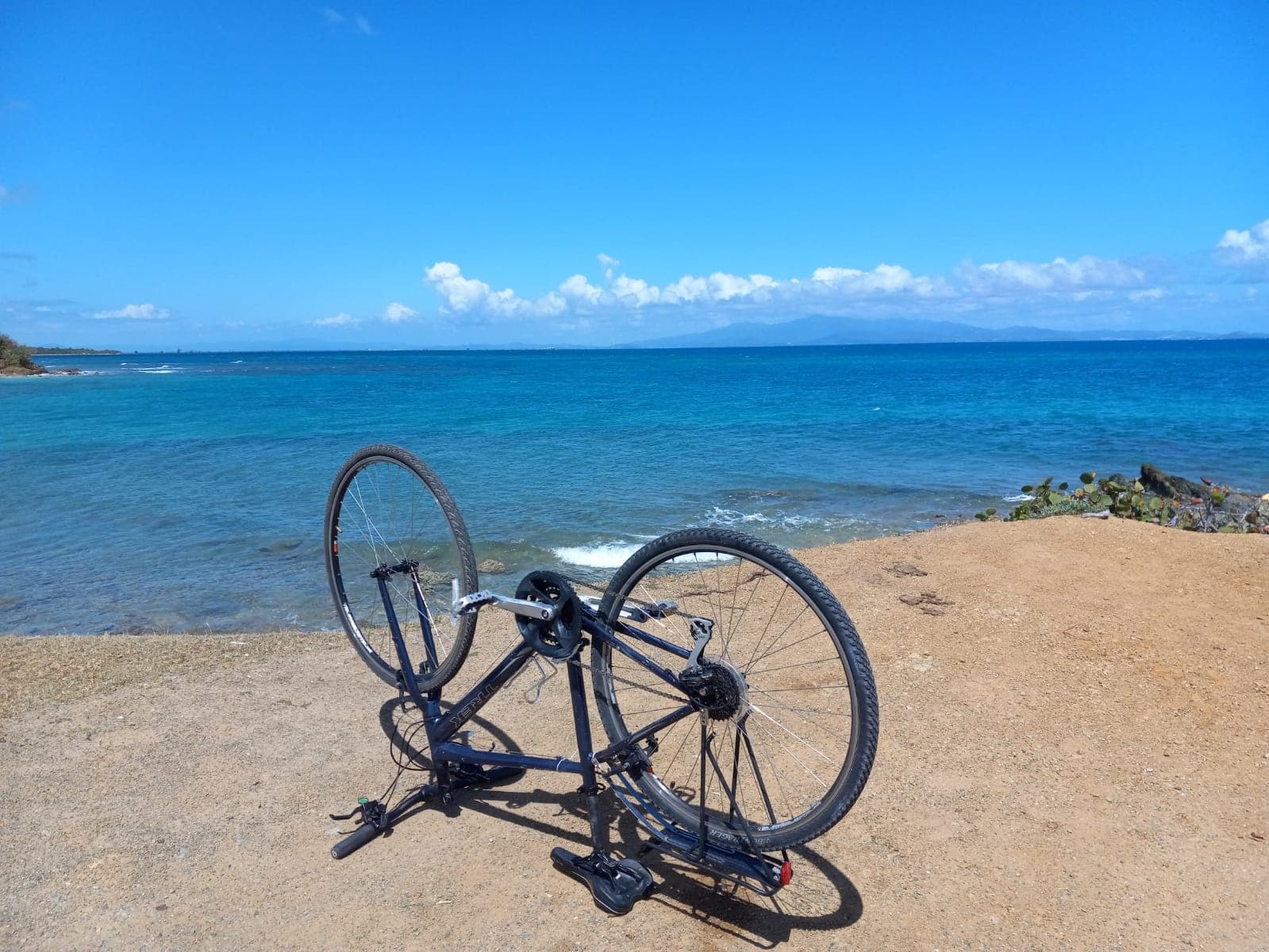 Road bike parked on sandy beach with turquoise ocean view