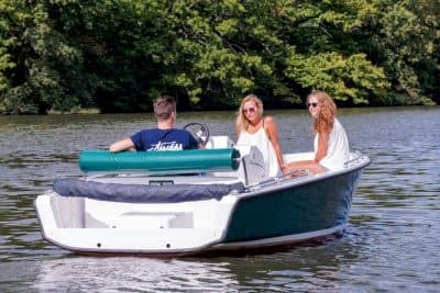 Friends cruising a scenic lake in a green leisure boat