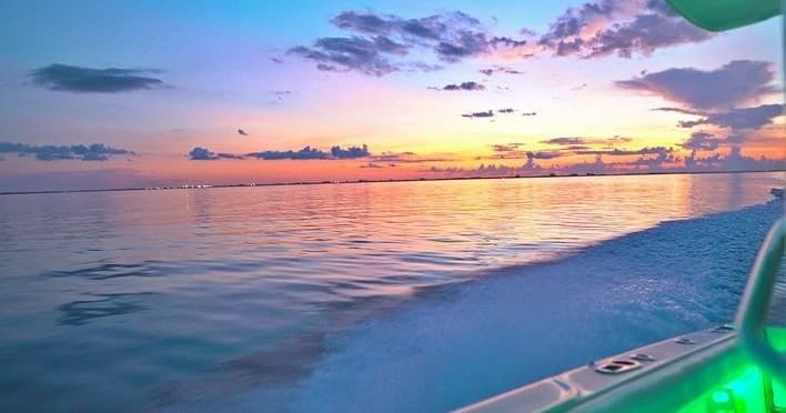 Boat cruising at sunset over calm Caribbean sea near Cayman Islands