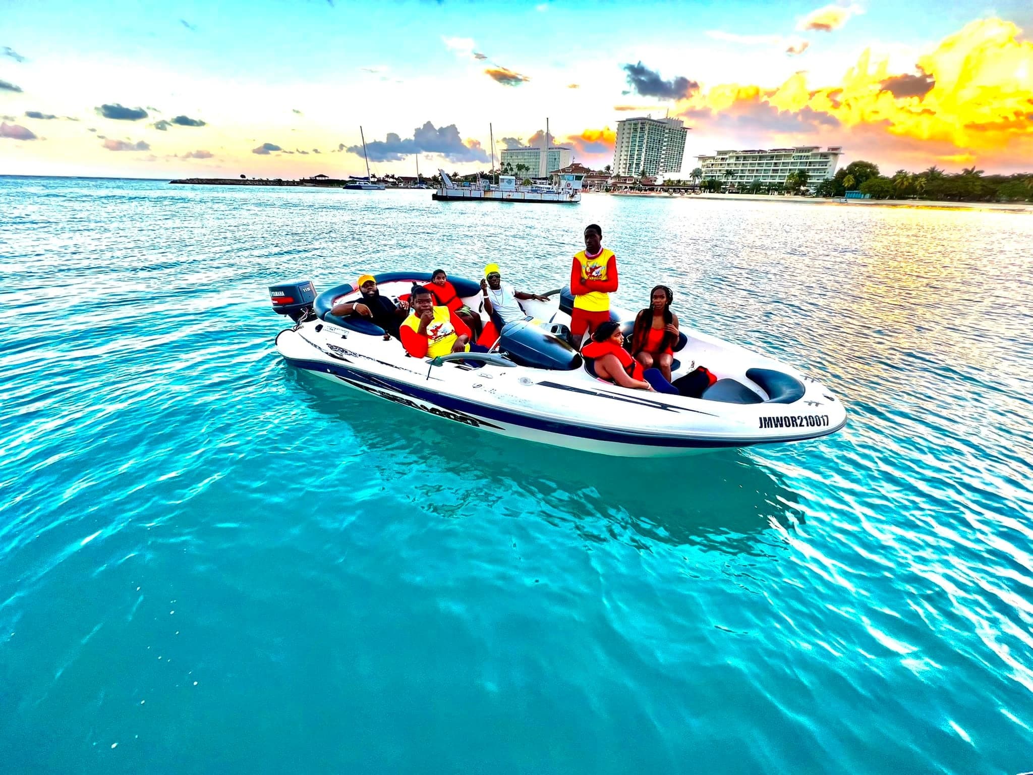 Speedboat cruising turquoise bay at sunset with excited crew