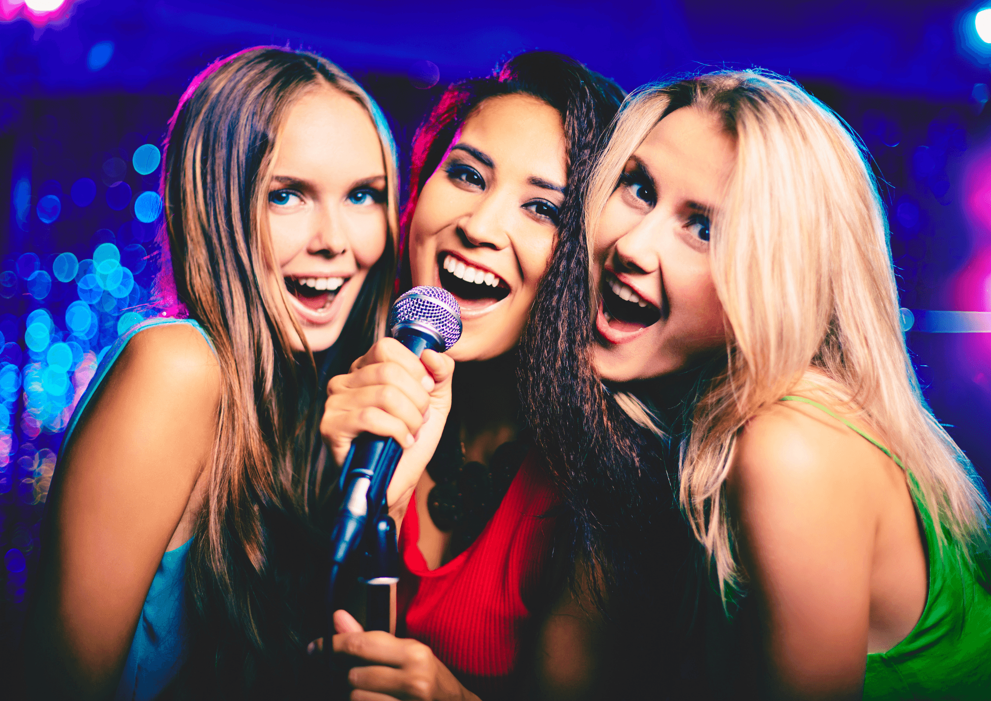 Friends singing karaoke on stage at lively indoor nightclub