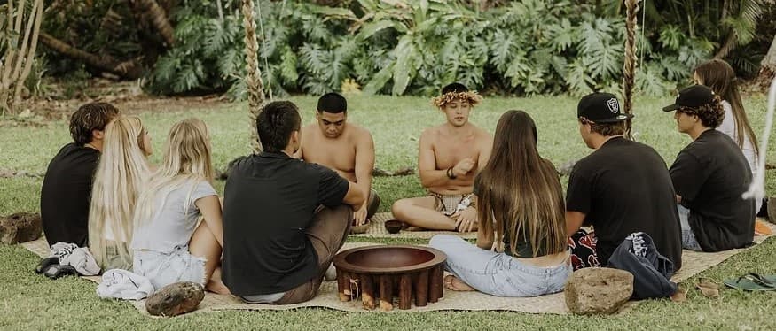 Outdoor group circle drumming and storytelling on grassy field
