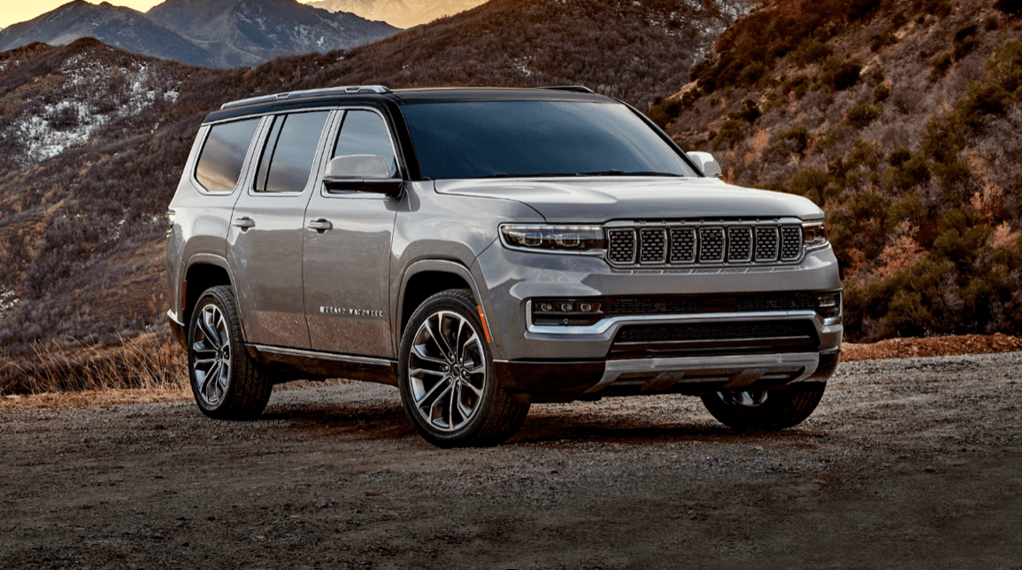 Silver SUV parked by rugged mountain trail showcasing scenic vista