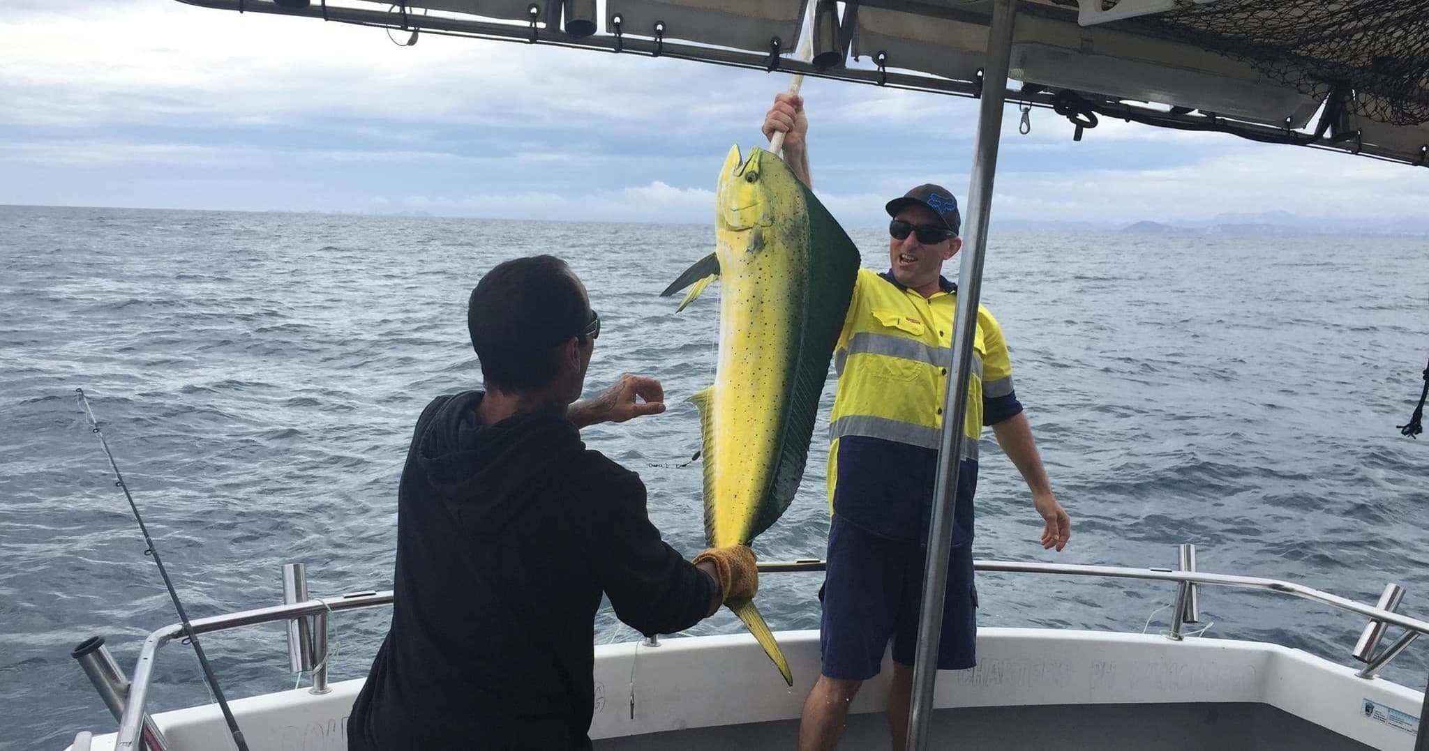 Angler hauling large mahi on deck in open ocean