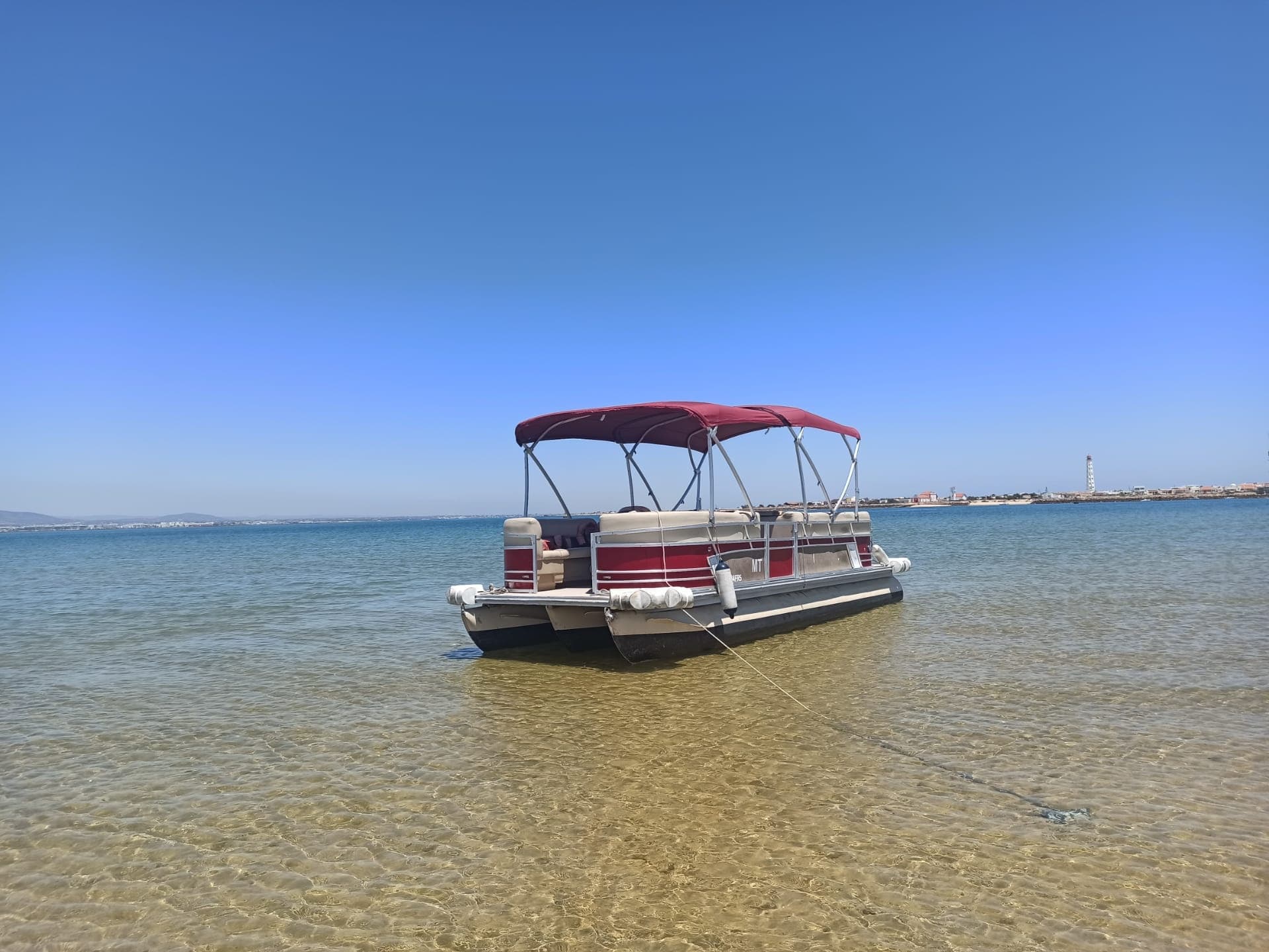 Pontoon boat stranded in shallow clear coastal waters on sandbar