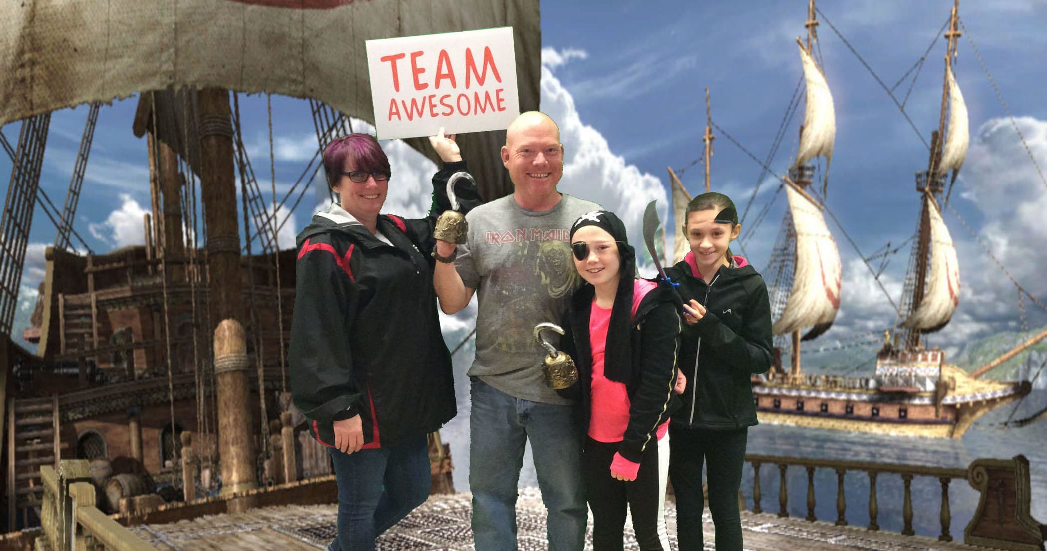 Family posing by historic sailing ship set at seaside pier